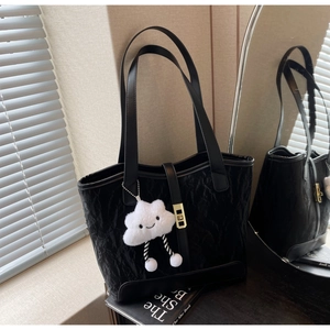 Detail of black pleated tote bag with golden buckle and cute white cloud charm