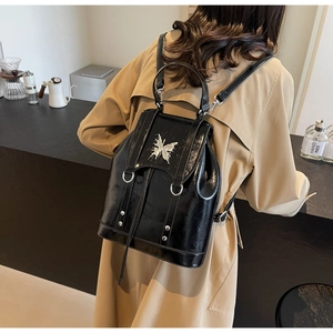 Detail of black patent leather backpack with silver butterfly buckle and rivet accents