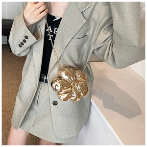 Close-up of a gold flower-shaped metal clutch with polished finish and gold chain strap
