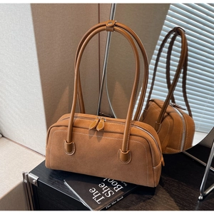 Detail of brown suede baguette bag with white stitching and dual metal zipper closure