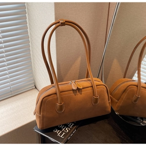 Close-up of brown suede shoulder bag featuring contrast white stitching and dual straps