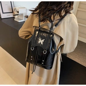 Detailed close-up of glossy black mini backpack with silver butterfly metal ornament