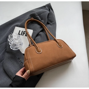 Detailed close-up of brown suede Boston bag with white stitching and leather handles