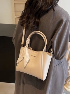 Chic beige bucket handbag with heart scarf on grey blazer, stylish crossbody bag fashion