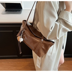 Detail of a brown glossy patent leather shoulder bag with creative baseball glove charm
