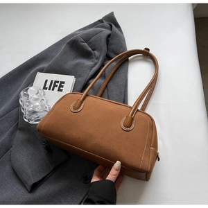 Detail of brown suede baguette bag featuring refined contrast white stitching and leather handle