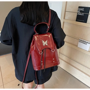 Detailed back view of a retro burgundy leather backpack with a silver butterfly buckle