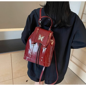 Close-up of glossy dark red backpack featuring a silver butterfly metallic clasp buckle
