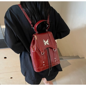Rear view of model wearing a vintage dark red backpack with silver butterfly detail