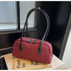 Detail view of burgundy frosted shoulder bag with white contrast stitching and dual zippers