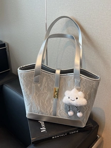 Silver-grey large tote bag with textured finish, gold buckle, and plush cloud charm