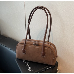 Detailed shot of dark brown suede bag featuring white contrast stitching and dual zippers