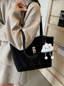 Black crinkled tote bag with golden twist lock and cloud charm, worn by model
