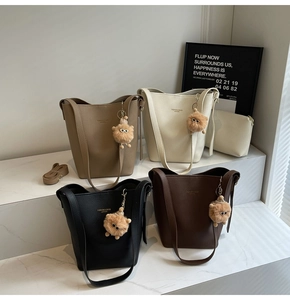 Detailed display of four vintage bucket bags in neutral colors with plush pendants