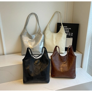 Detail view of four large patchwork leather tote bags in silver, beige, black, and brown