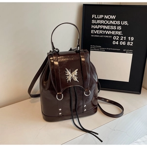 Detail of burgundy patent leather backpack with silver butterfly buckle and rivet accents