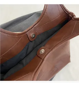 Detail of brown leather tote showing magnetic buckles and black fabric interior lining