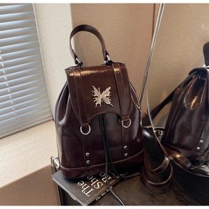 Detail of coffee glossy mini backpack with silver butterfly hardware and drawstring closure