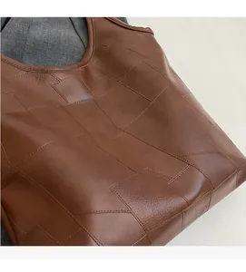 Detailed view of brown tote bag showing soft textured leather and geometric stitching