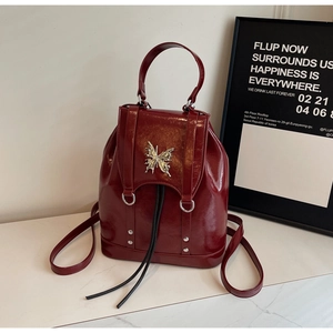 Close-up of dark red patent leather backpack with silver butterfly buckle and drawstring detail