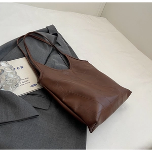 Detail of dark brown leather tote bag with geometric embossed texture for daily commute