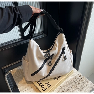 Detail of off-white nylon tote bag showing adjustable wide strap and zip closures