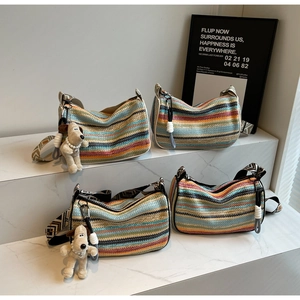 Detail of colorful striped straw shoulder bags with patterned wide straps and cute charms