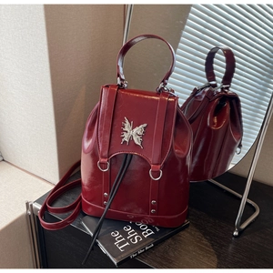 Detailed shot of dark red patent leather backpack with silver butterfly metal ornament