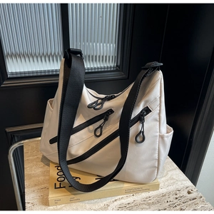 Detail of off-white nylon tote bag with black contrast zippers and adjustable strap