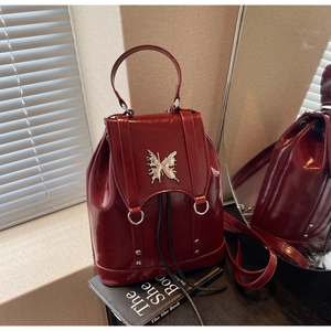 Detail of red patent leather backpack featuring silver butterfly hardware and metal rivets