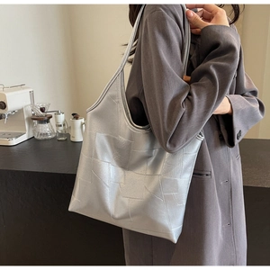 Detailed side view of silver geometric tote bag with metallic finish on model