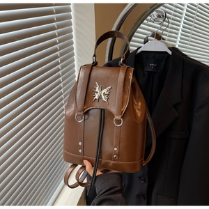 Detail of dark brown vintage backpack with silver butterfly metal ornament and flap cover