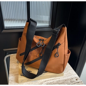 Brown nylon tote bag detail with three diagonal zippers and adjustable shoulder strap
