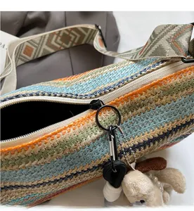 Detail of colorful striped woven crossbody bag with smooth zipper and plush dog charm