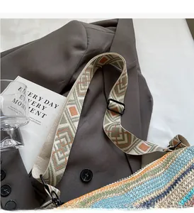 Detail of colorful woven straw bag with geometric patterned strap and black metal hardware