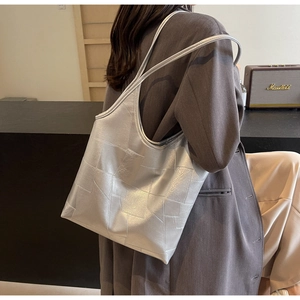 Silver geometric patchwork tote bag shown on model in a stylish commute setting