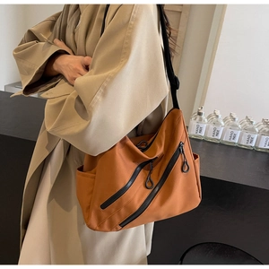 Detail view of the caramel nylon tote showing functional black zippers and wide strap