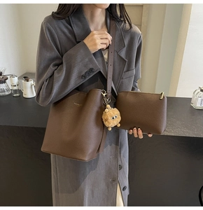 Detail view of brown leather bucket bag set with matching pouch and plush pendant charm