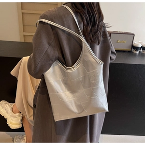 Silver tote bag with geometric texture worn by model in a minimalist lifestyle setting