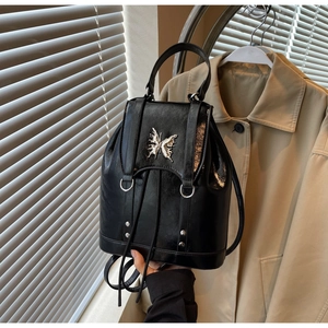 Detail of a vintage black leather backpack featuring a silver butterfly metal buckle