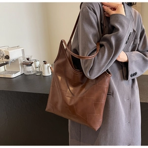 Detail of vintage brown leather tote bag with geometric patchwork and long handles