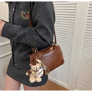 Détail d'un sac carré rétro en similicuir marron avec une breloque d'ours en peluche