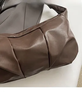 Macro detail of the dark brown ruched faux leather texture on soft casual shoulder bag
