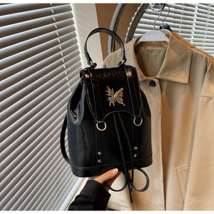 Detail of black patent leather backpack with gold butterfly relief and metal studs