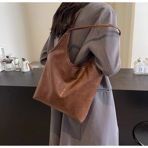 Detail of vintage brown leather patchwork tote bag showing large capacity on model
