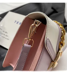 Detail of pink and lilac leather handbag with luxury gold chain and metallic buckle