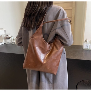 Detail of vintage brown patchwork leather tote bag worn with a gray coat