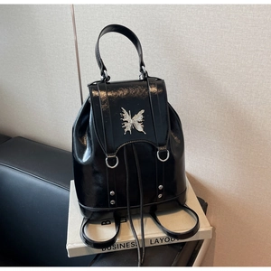 Detail of glossy black backpack featuring a silver butterfly buckle and drawstring closure