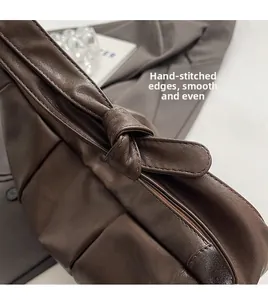 Detailed macro view of dark brown leather shoulder bag with twisted knot and hand-stitched edges