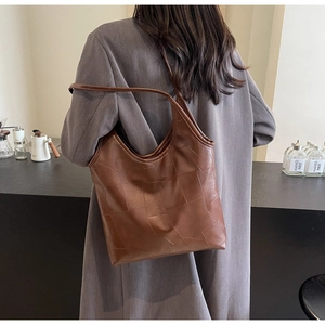 Detail of vintage brown leather tote bag with geometric embossed texture on shoulder